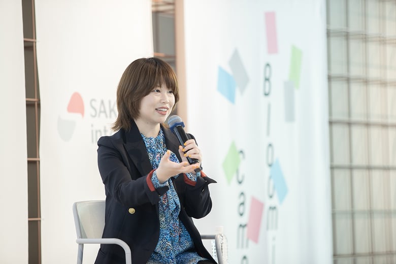 岸田さんがマイクを持ち、笑顔で身振りを交えながら話している様子
