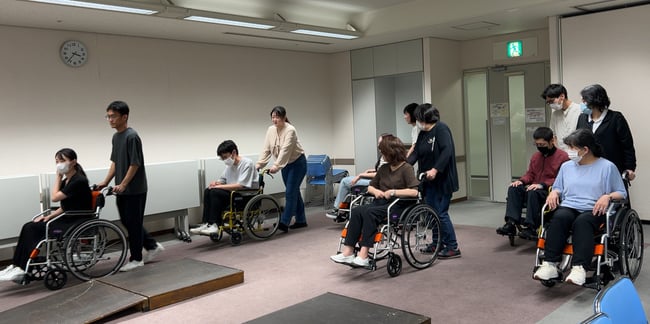 写真　車いす実技研修で車いすのサポート方法を学んでいる様子