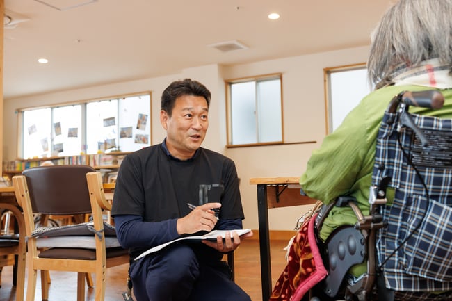 写真　正和工業の吉本さんが車いすユーザーと目線を合わせて話している様子