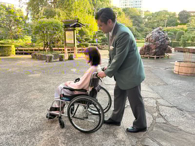 （写真）ニューオータニの社員が外で車いすユーザーをサポートしている様子