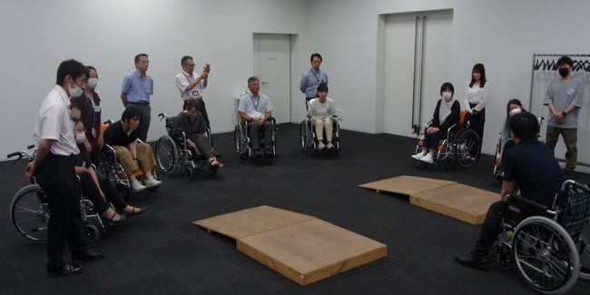（写真）講師が車いす実技研修で車いすの説明を行っている様子