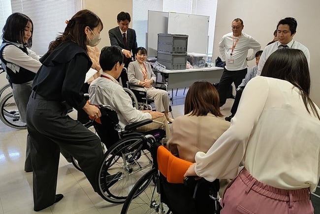 （写真）車いす実技研修の中で、車いすに乗っている方へのサポート方法を実践している様子