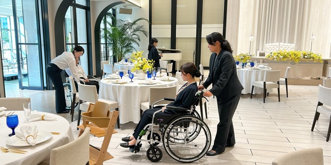 （写真）車いす実技研修で受講者が車いすのサポート方法を実践している様子