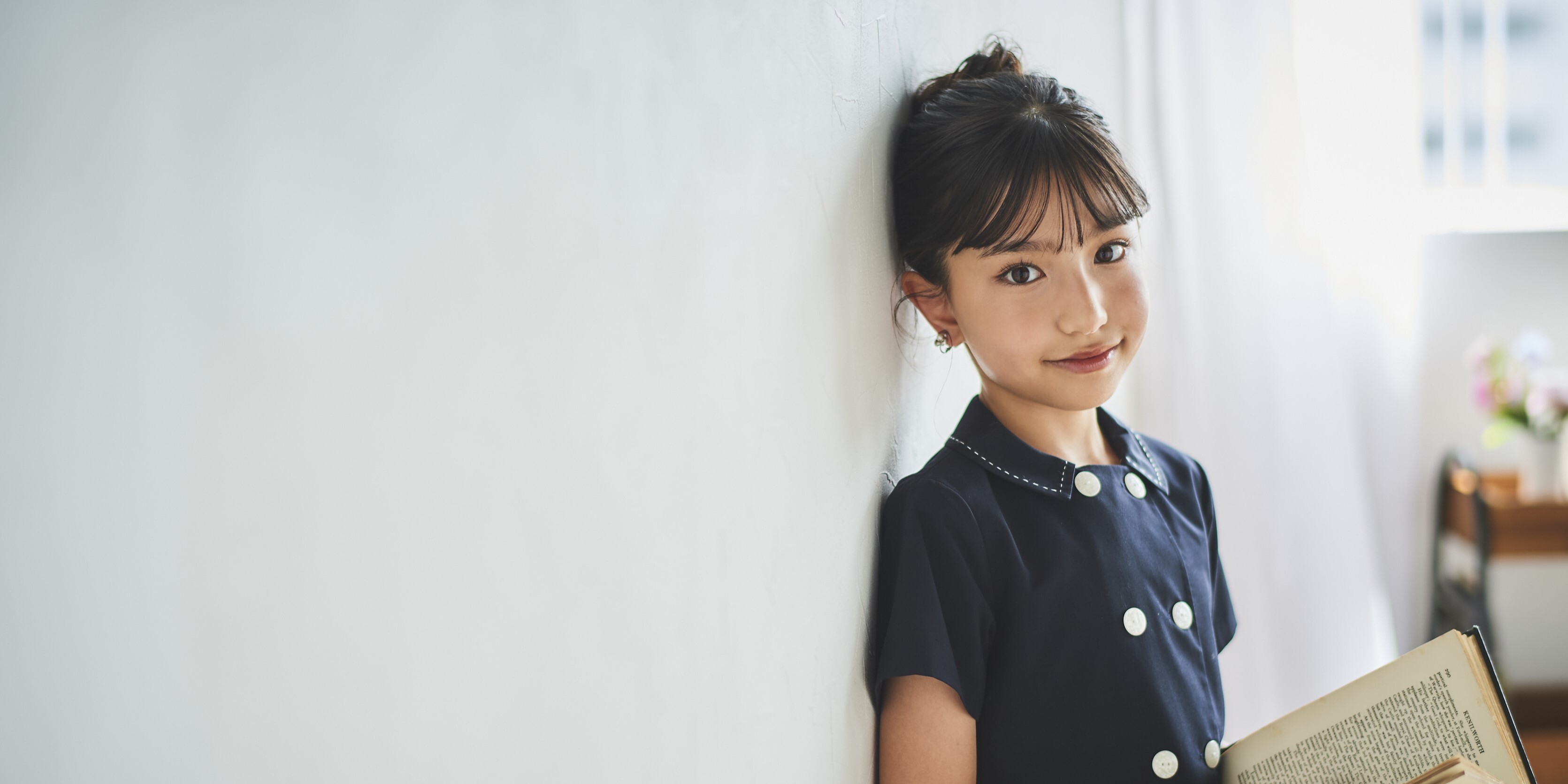（写真）大野りりあなさんが壁に寄りかかりながら本を持っている写真