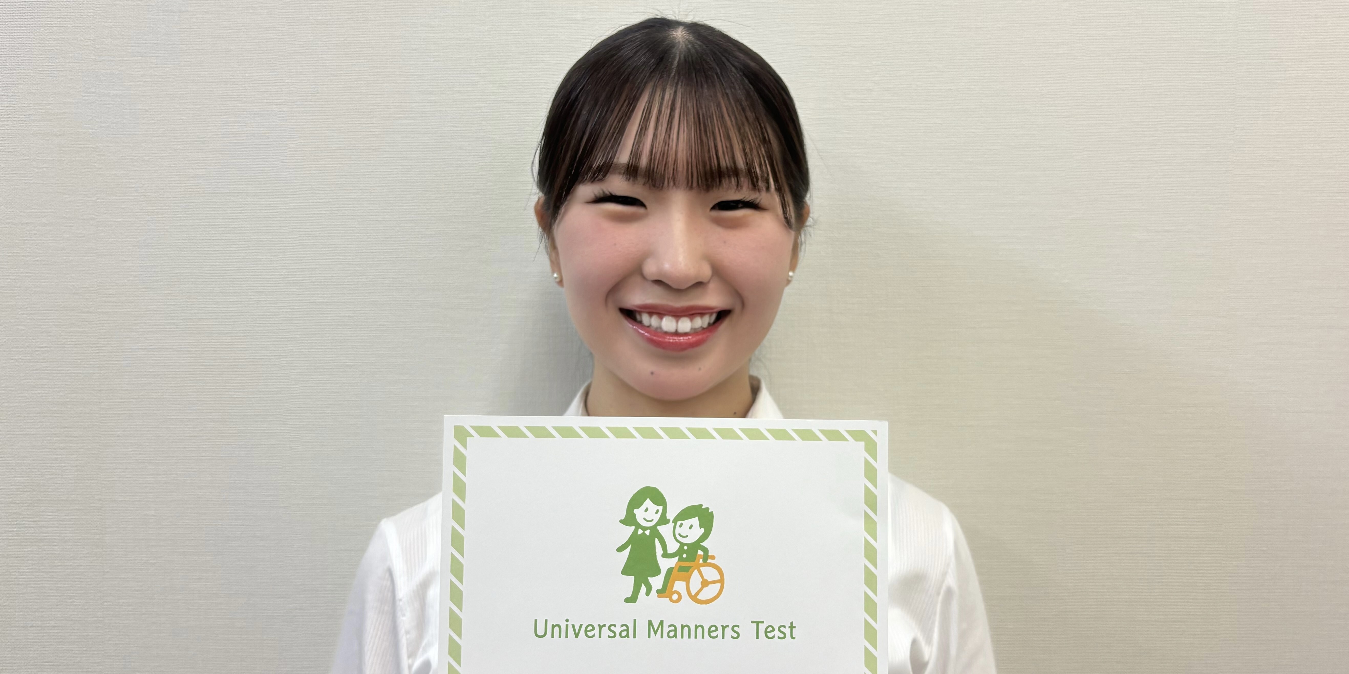 (写真)鈴木さんがユニバーサルマナー検定2級の認定証を持っている様子
